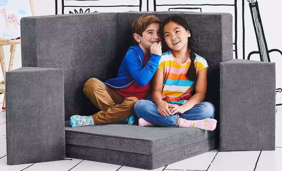 a boy and girl sitting on a yourigami couch cushion