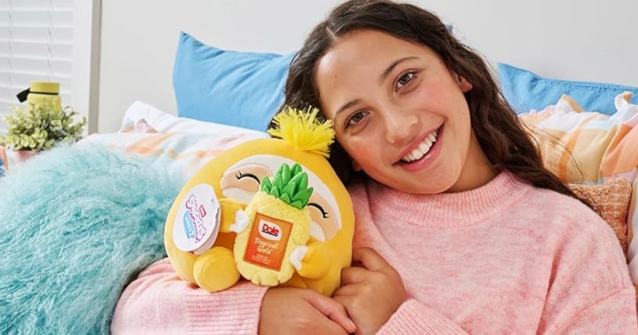 girl holding pineapple snackle plush 