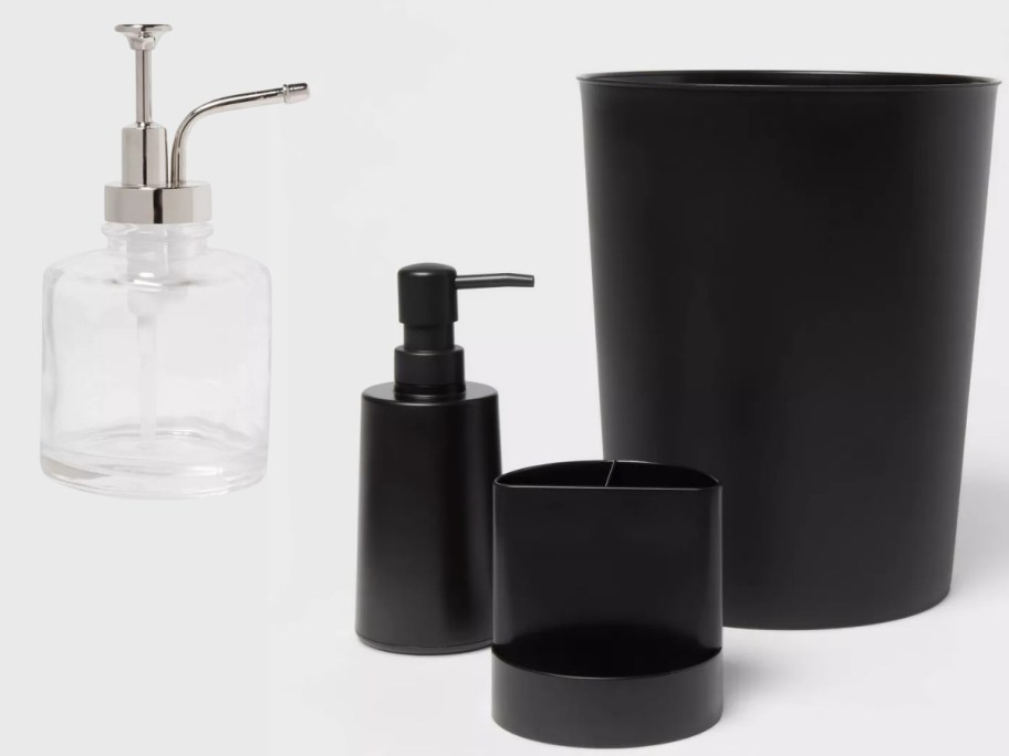 a glass soap pump with a silver handle pump that looks like an oil can and a set of a black bathroom trashcan, soap dispenser and toothbrush holder