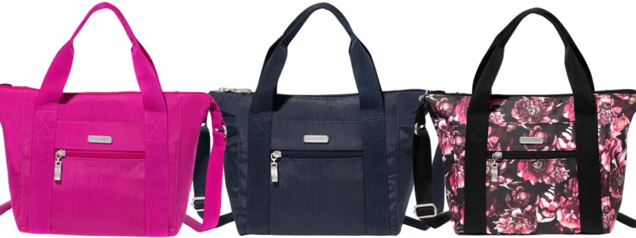 3 Baggalini tote bag purses with handles and straps, one is bright pink, one is navy blue, and one is black with pink flowers