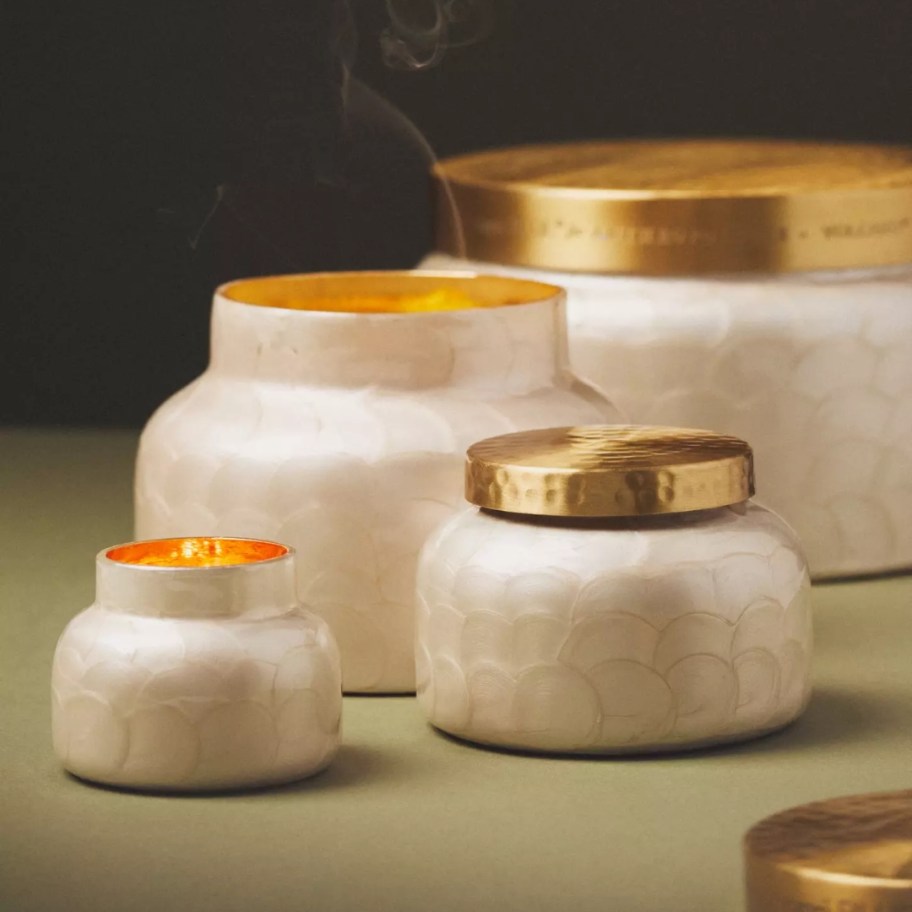 glass jar candles in a cream color with gold lids in various sizes