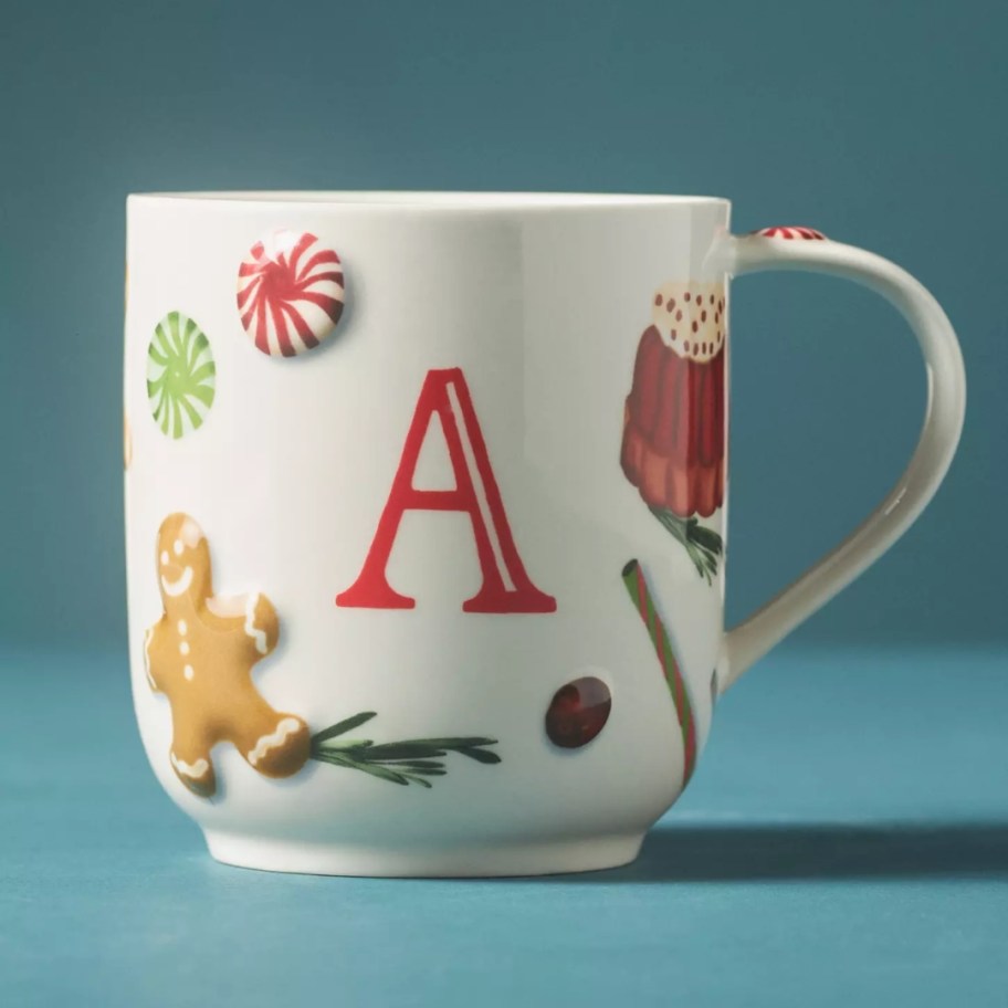 a Christmas coffee mug with the letter A on it, gingerbread man, peppermint and other holiday items