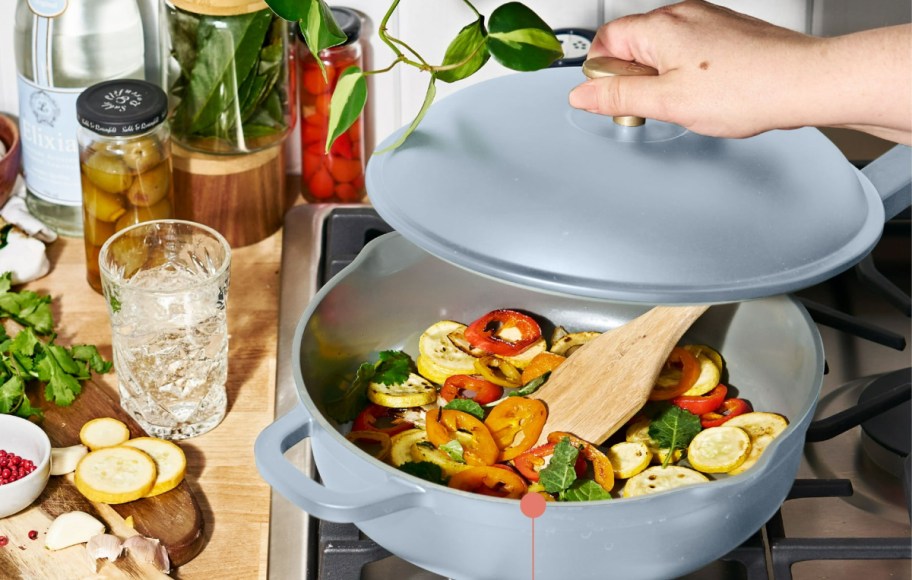 Beautiful All-in-One 4 QT Hero Pan with hand holding the lid