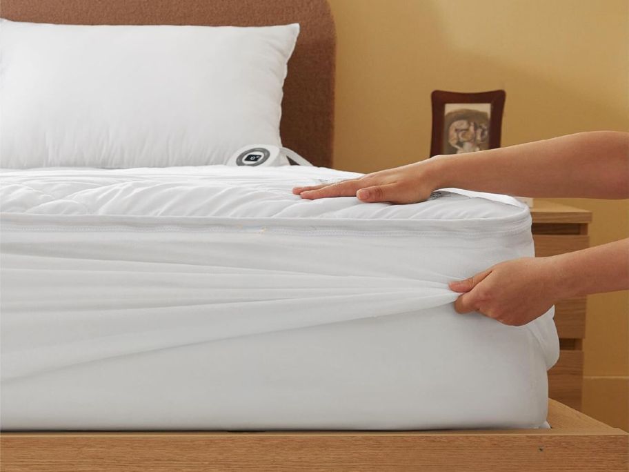 hands putting on Bedsure Removable Heated Mattress Pad on bed