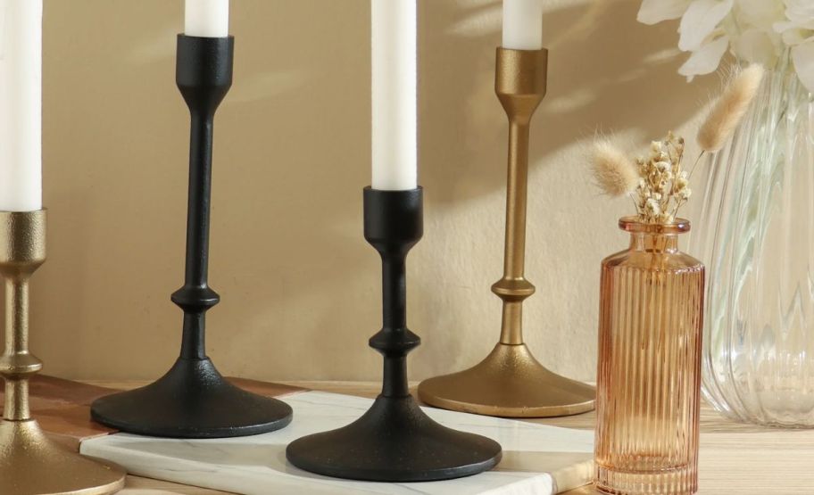 2 cast iron taper candle holders shown with 2 brass ones