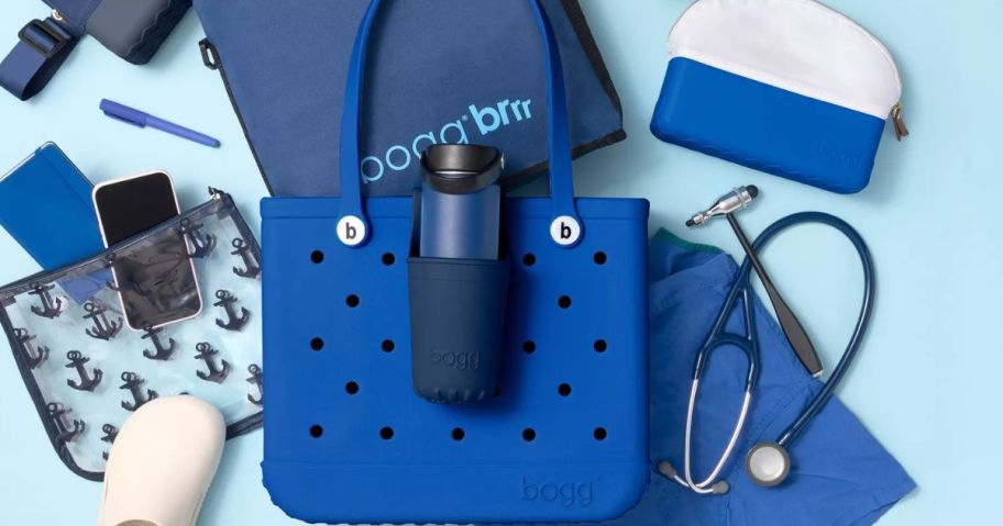 A bogg bag surrounded by carious bogg accessories, a sthethoscope, clogs and nursing items