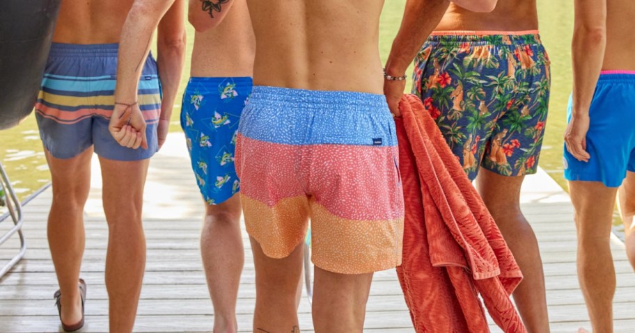 4 men wearing chubbies swimwear and walking away from camera on dock