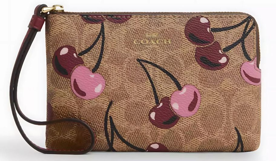 A tan Coach Wristlet with cherries on it 