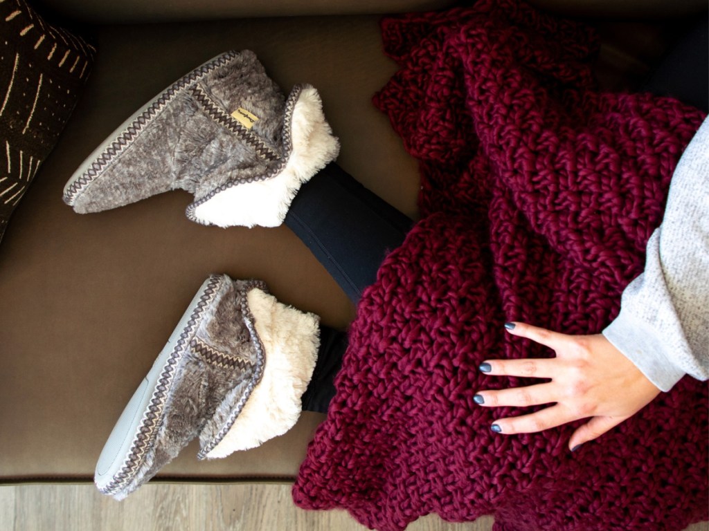 woman wearing gray dearfoams sippers and snuggling with blanket