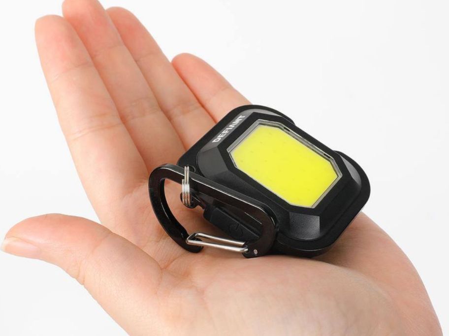 a hand holding a mini utility light