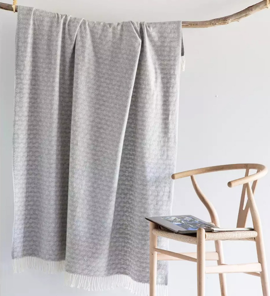 grey throw hanging from a branch near a chair