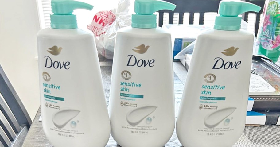 three large bottles of dove sensitive skin body wash on table