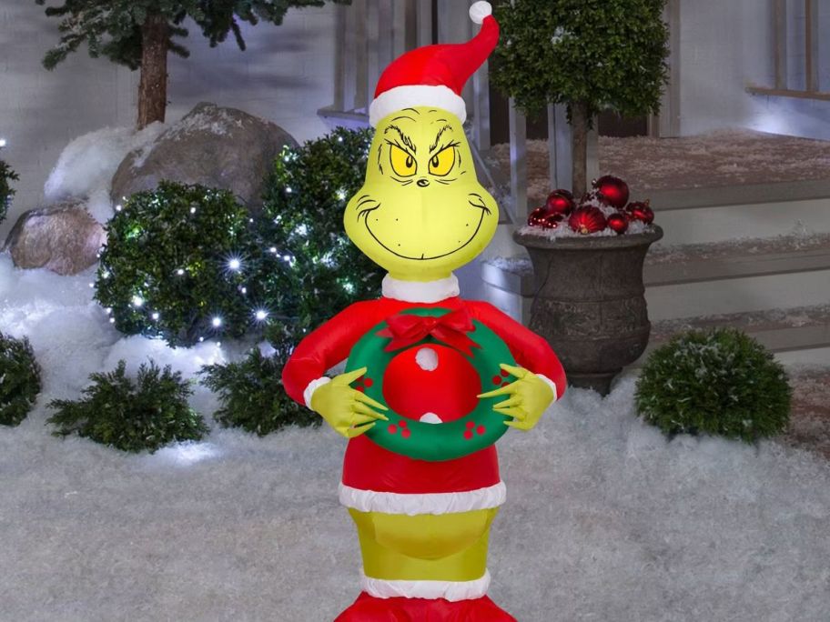 Dr. Seuss Grinch as Santa in the snow in front of a house