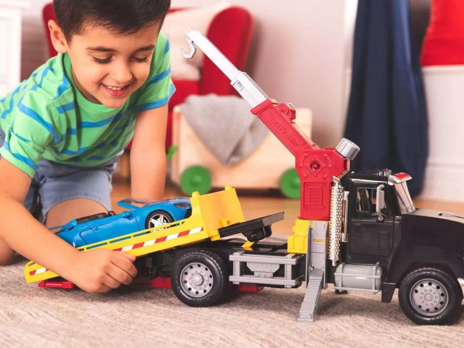 Little boy playing with a Driven by Battat Tow Truck