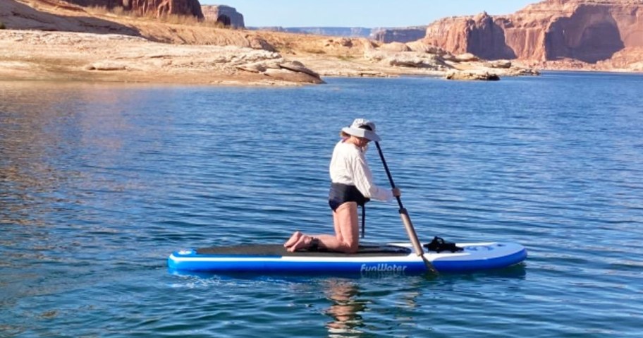 woman kneeling on a paddle board in water