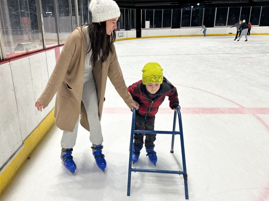 Woman helping a little boy ice skate at a rink