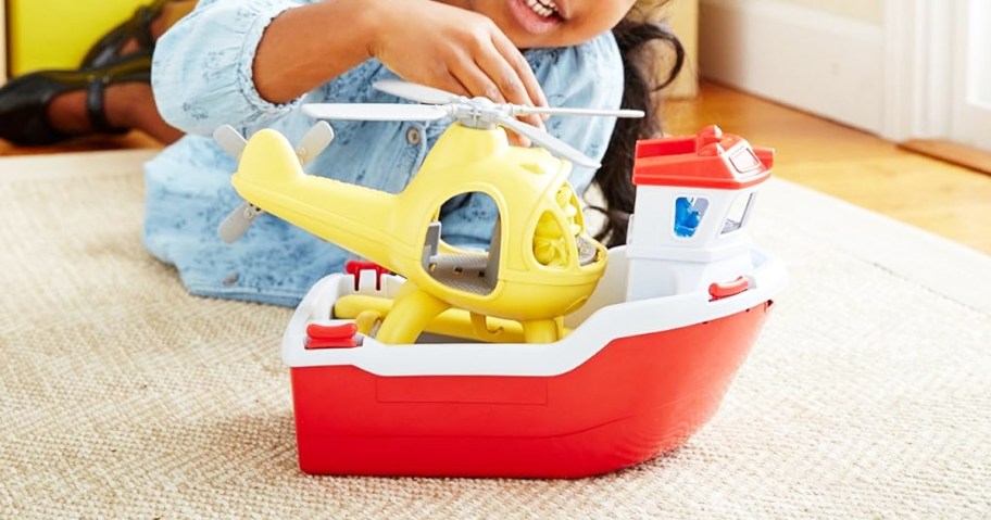 girl laying on floor playing with Green Toys Rescue Boat with Helicopter