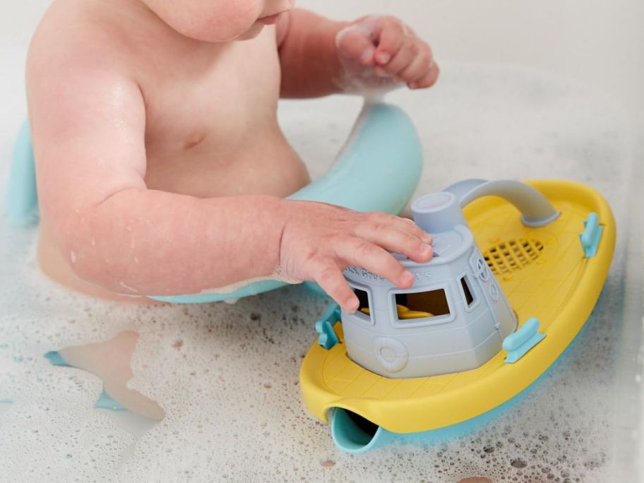 Baby playing in the tub with a Green Toys Tug Boat