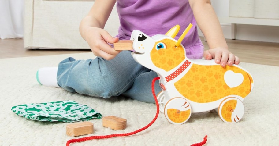 girl playing with a wooden pull dog toy