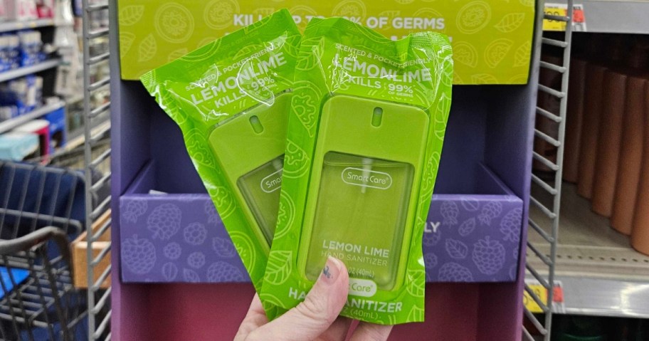 hand holding 2 green color hand sanitizers in the packaging they come in