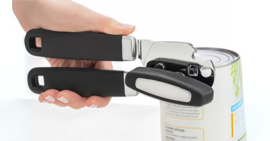 person using a black and white manual can opener to open a can