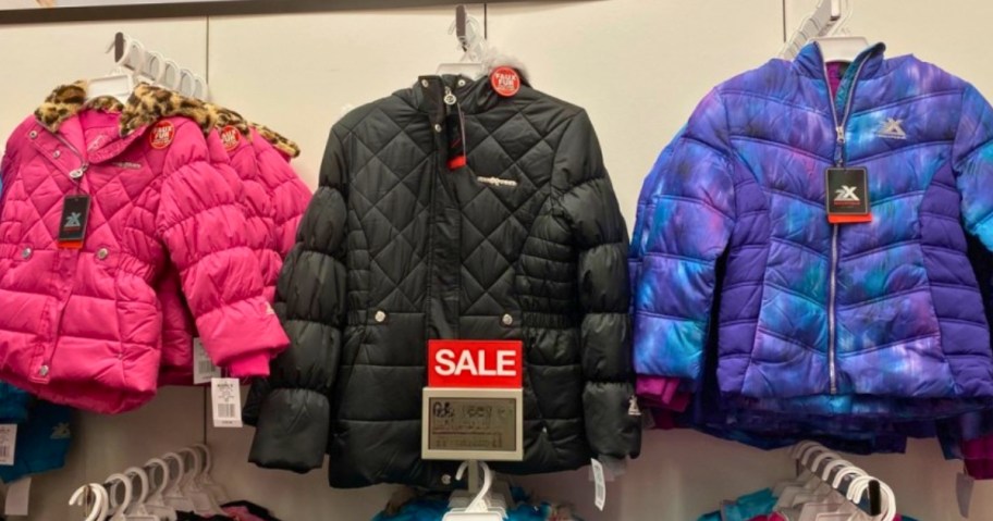 kids winter puffer style coats hanging on a store display wall