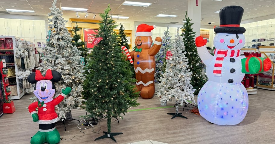 the Christmas section in a Kohl's store with Christmas trees, some green, some white flocked, and large Christmas Inflatable Snowman, Gingerbread man, and Minnie Mouse