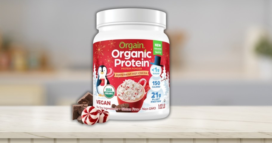 a red and white container of Orgain peppermint cocoa protein powder on a counter