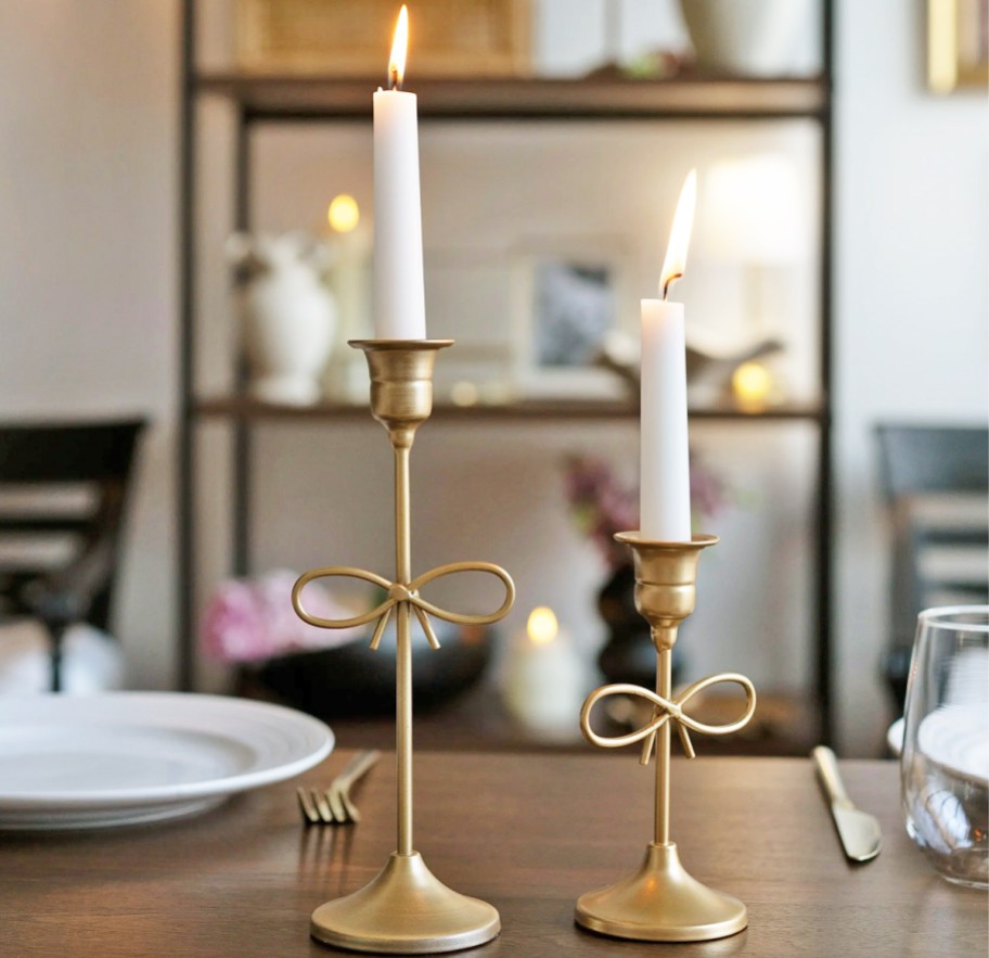 two gold bow candle holders on a table