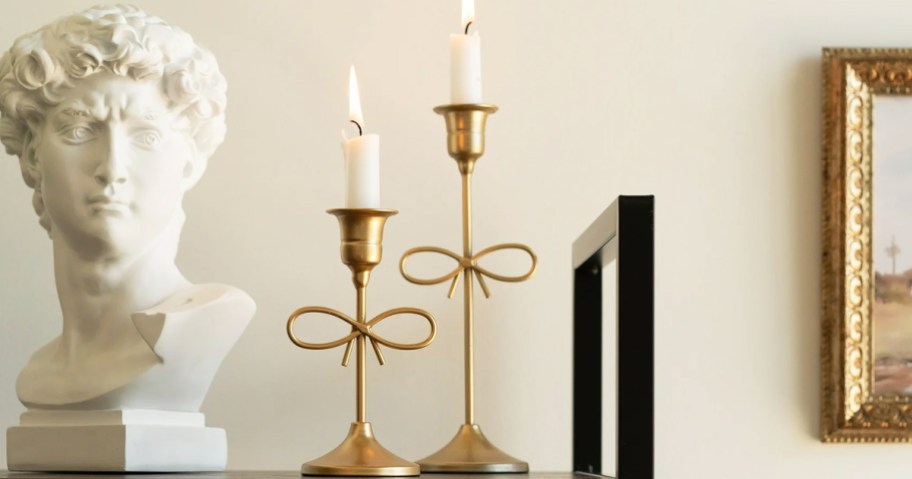two gold bow candle holders on a bookcase