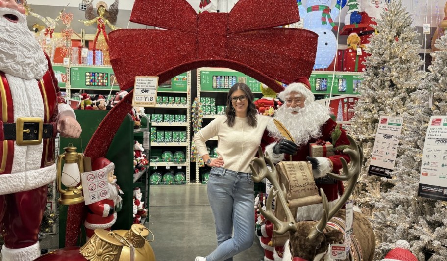 woman standing with santa statue and christmas decor at home depot