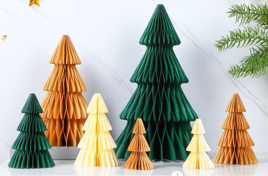 green, gold, and white paper christmas trees set displayed on table