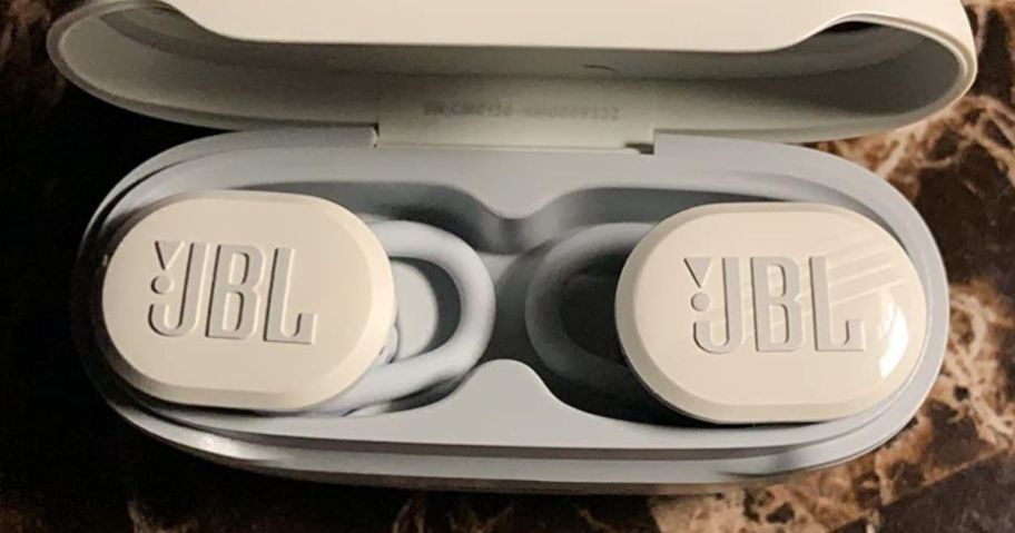 A pair of white JBL Earbuds in the charging case