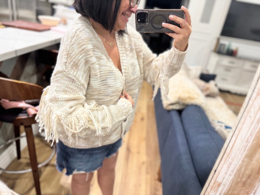 woman wearing fringe sweater taking selfie of side profile in mirror