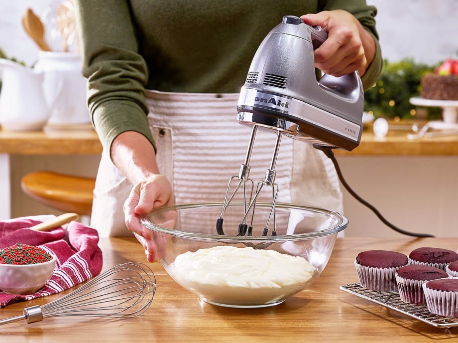 woman using silver hand mixer to make frosting