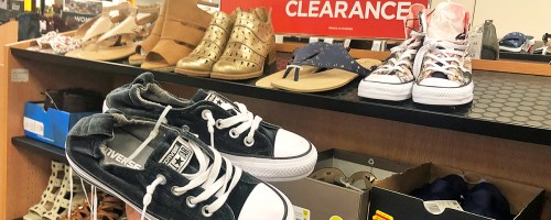 holding up a pair of converse near a rack of clearance shoes