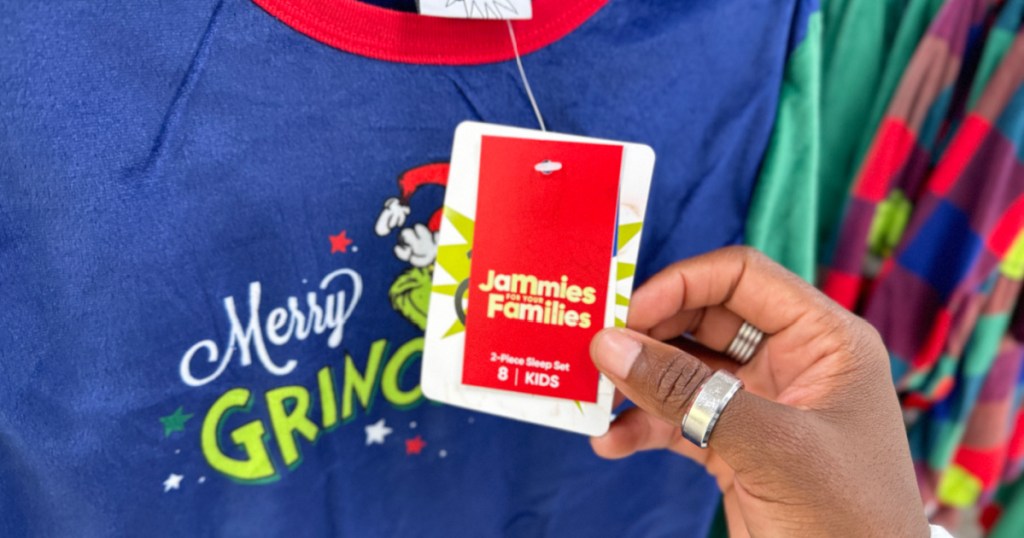 person holding grinch jammies tag inside kohls store