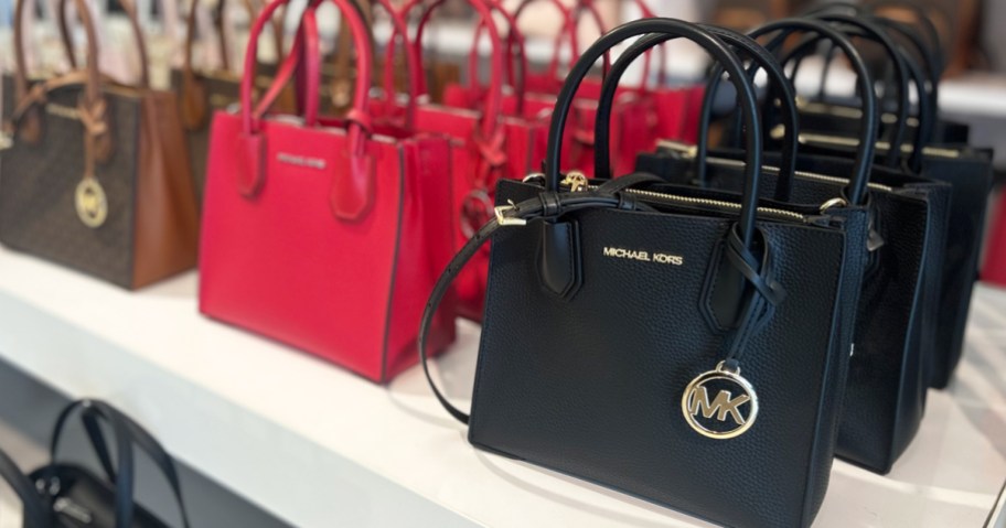 Michael Kors bags on a white store display table