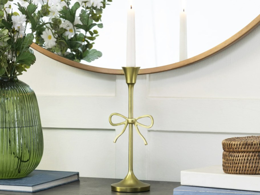 gold bow taper candle holder on a console table
