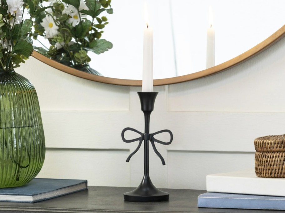 black bow taper candle holder on a console table