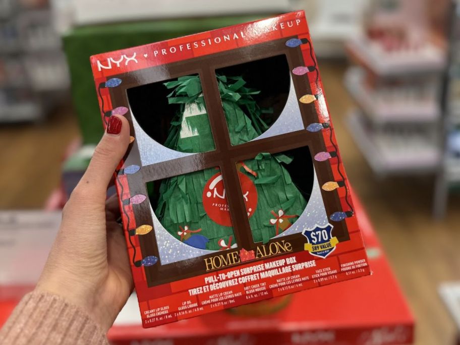 a womans hand holding an NYX home alone 12 piece pinata make up gift 