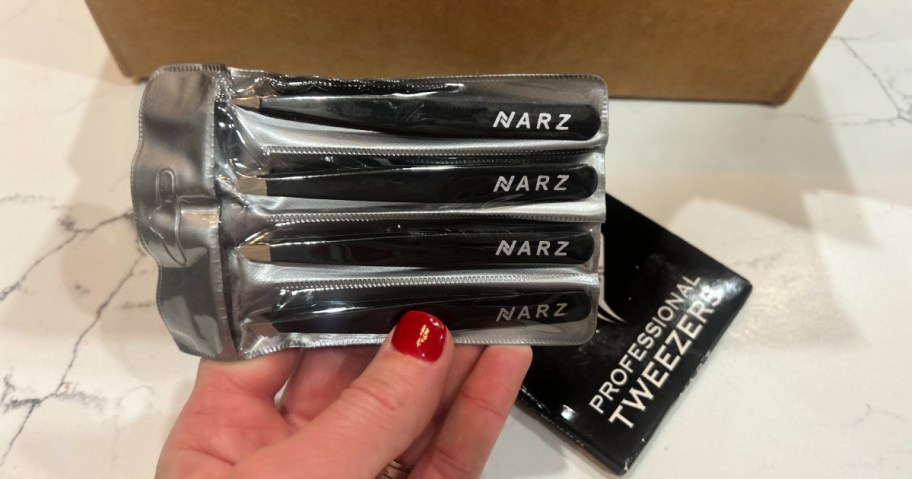 woman holding up package of nars tweezers