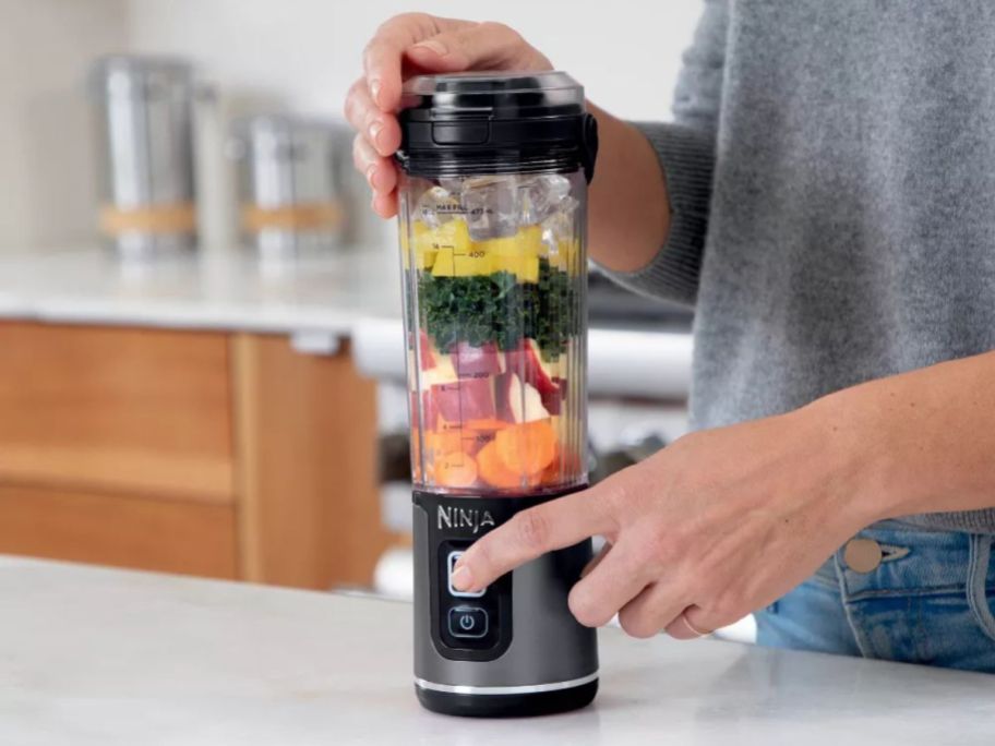 person using Ninja Blast 18oz Portable Blender in kitchen