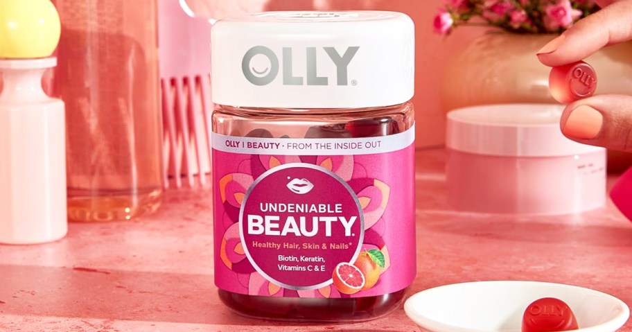 bottle of OLLY Undeniable Beauty Gummies with person taking a gummy from a plate