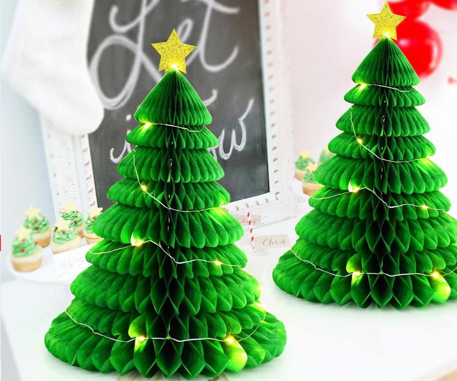 two green paper christmas trees wrapped in fairy lights