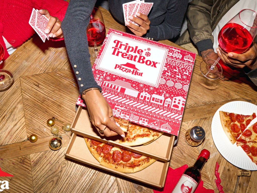 person grabbing slice of pizza from pizza hut triple treat box