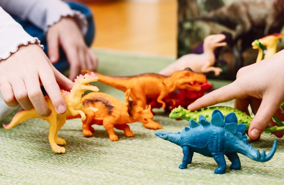 two kids playing with dinosaur toys