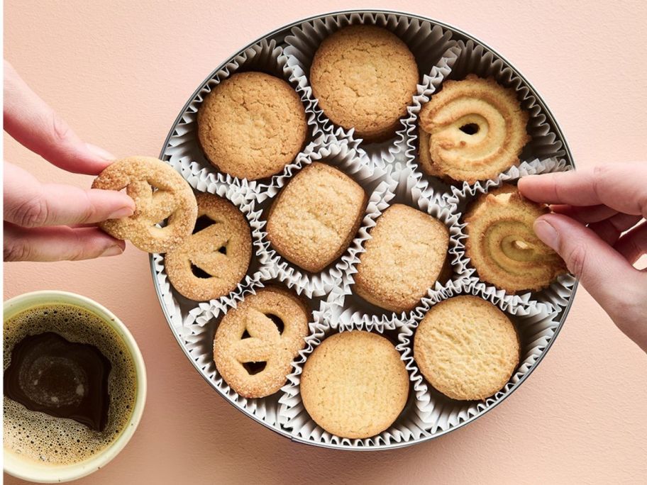 Hands taking cookies out of a tin of Royal Dansk Cookies