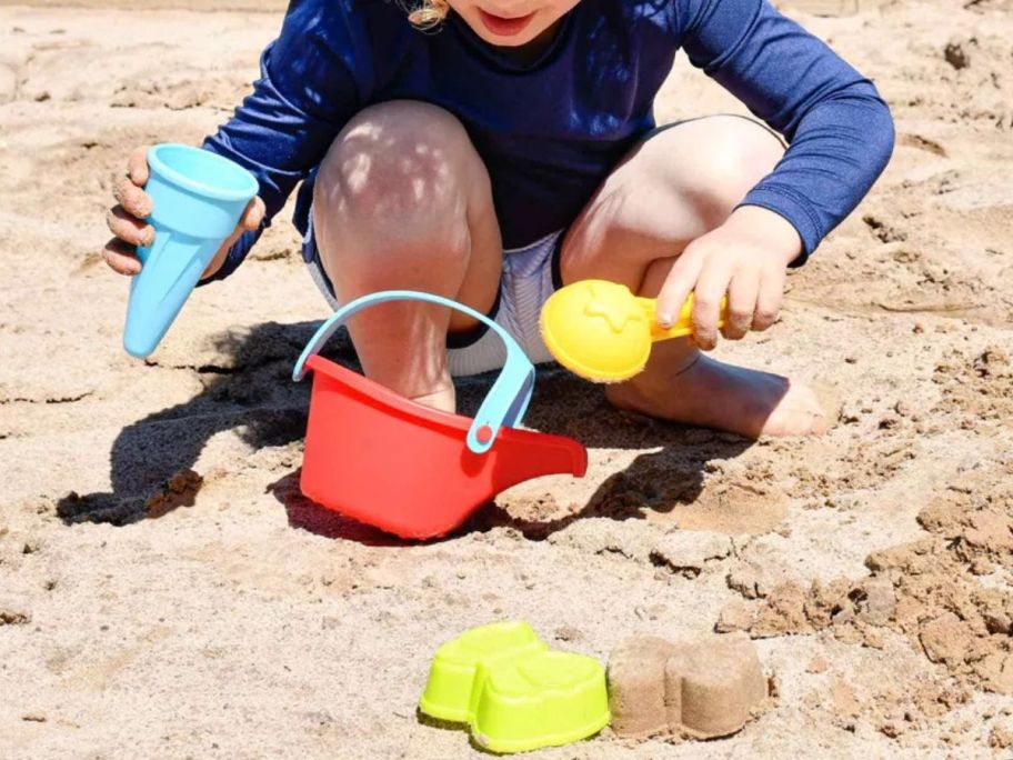 Little boy playing on the beach with sand toys