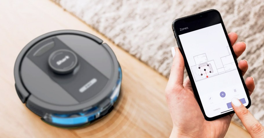 person holding phone with app to control shark robot vacuum